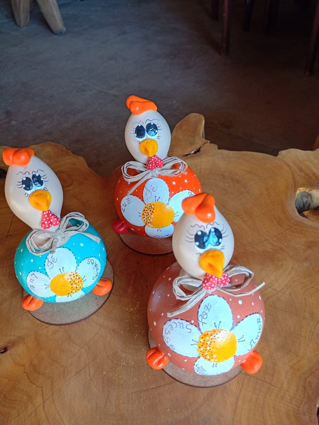 Trio de galinhas decorativas de cabaça com flores e palavras como Fé, Luz e Sucesso pintadas no corpo